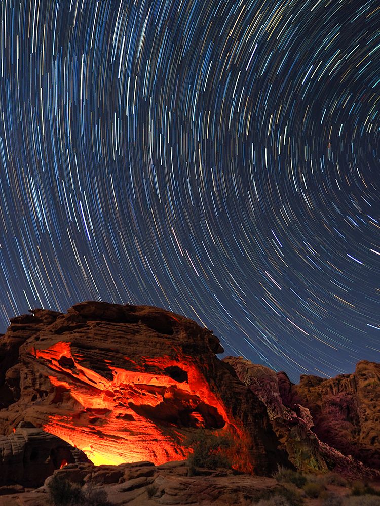 Usa-Nevada. Valley of Fire State Park-star trails and campfire glowing in sandstone rocks